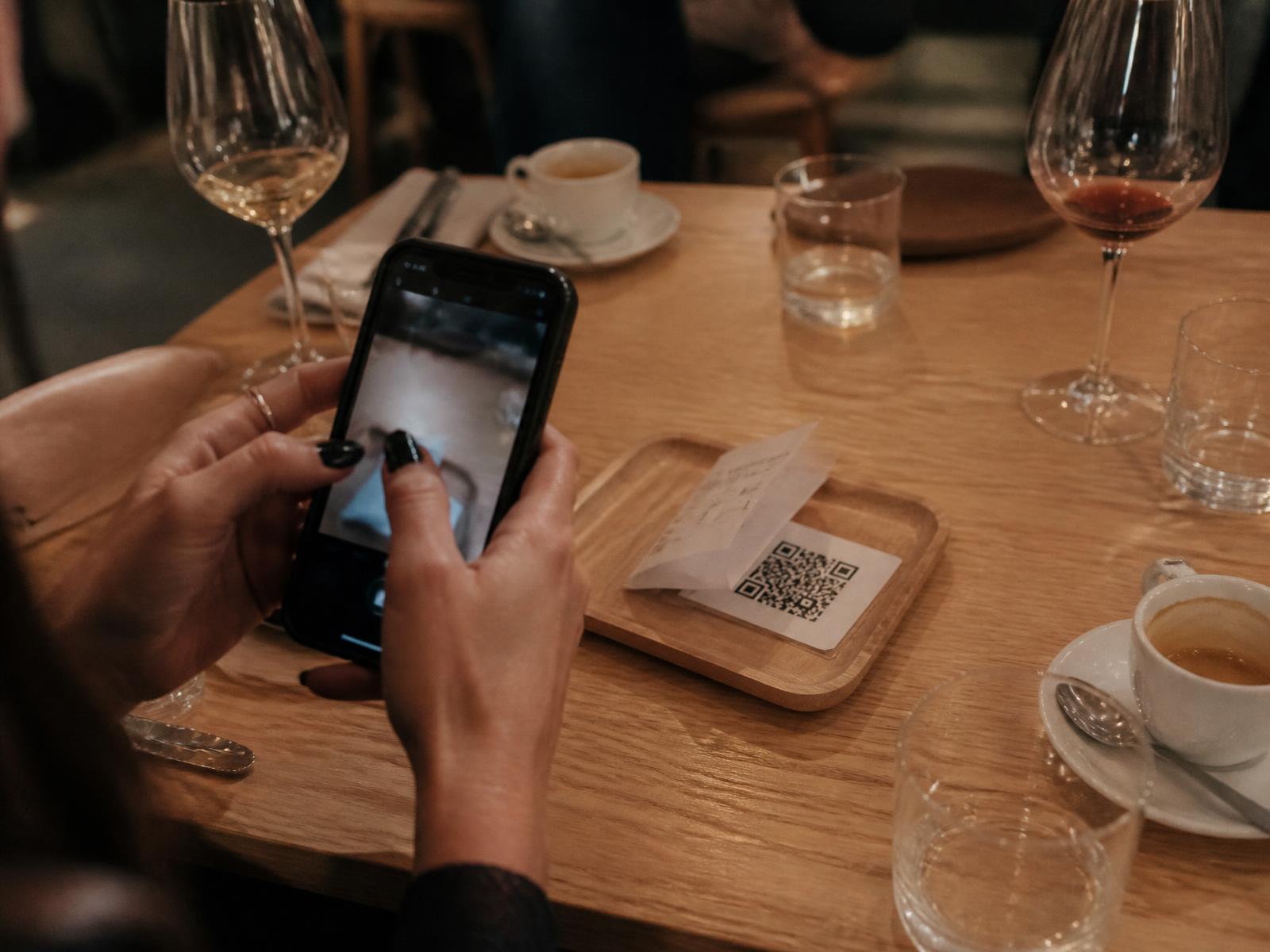 Kelner legt de rekening met QR-code op tafel in een restaurant